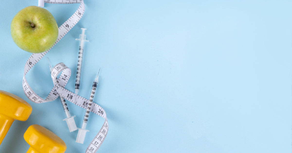 Weight loss concept with green apple, measuring tape, yellow dumbbells, and syringes representing Semaglutide Injections in Duluth, GA, on a light blue background.